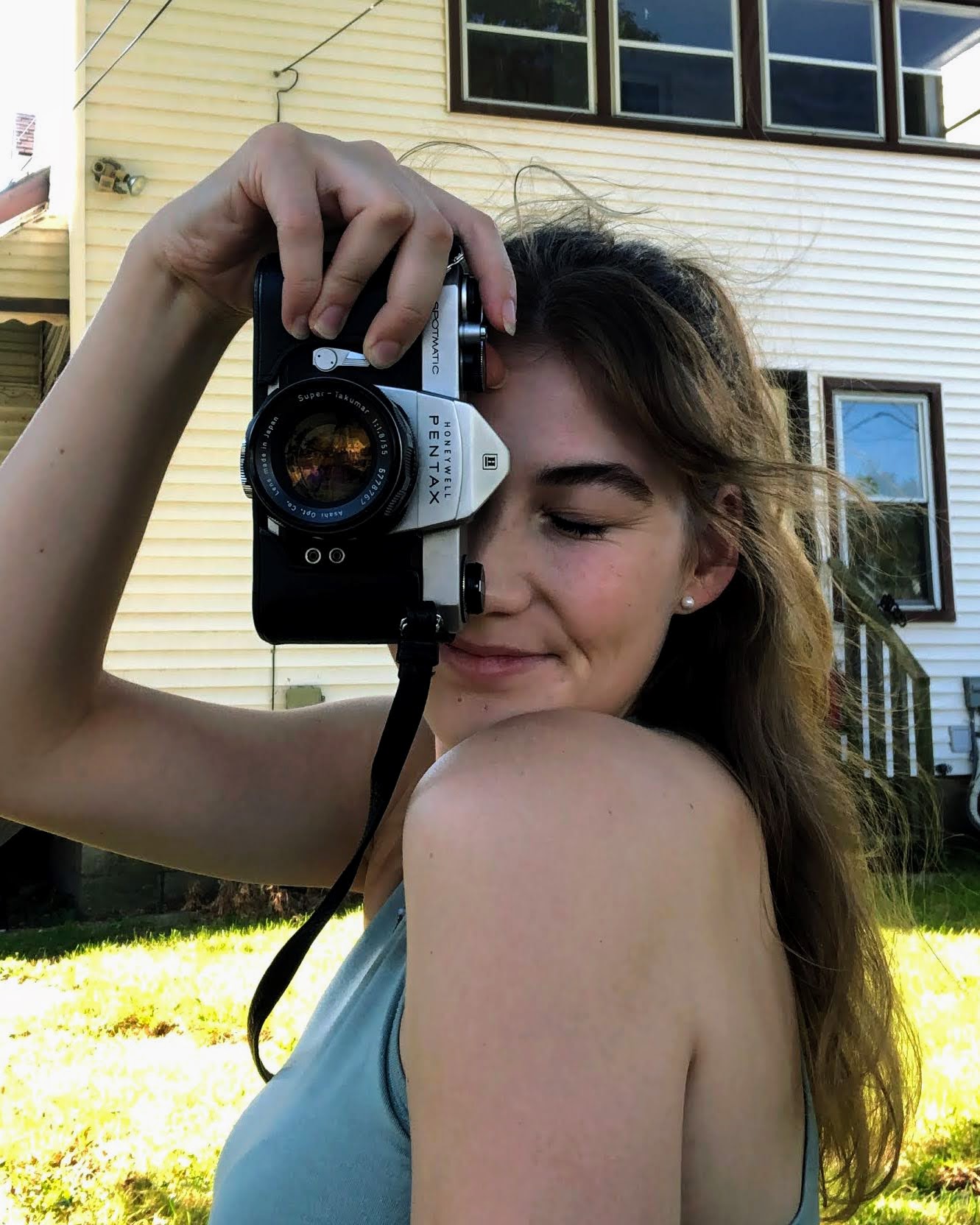 Portrait of a women with camera standing in front of a building.